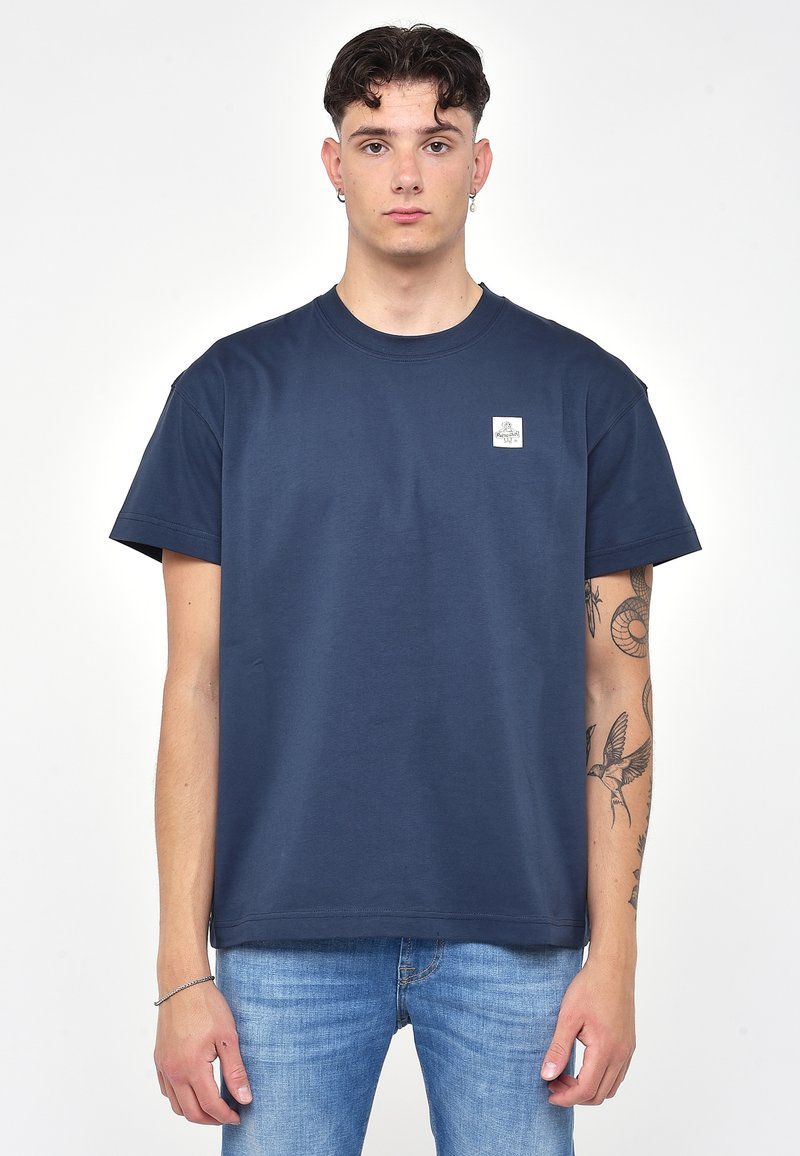 Námorně modré bavlněné tričko s kulatým výstřihem a krátkými rukávy. Obsahuje malou nášivku loga na levé části hrudi. Hladká textura, volný střih.