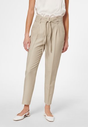 Beige tapered broek met een subtiele streepprint, hoge taille, strikbanden en zijzakken. Gecombineerd met witte slingback flats.