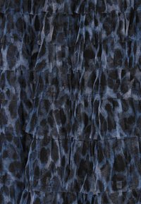 Kék és fekete téglalap alakú szövet, leopárd mintázattal és áttetsző textúrával. A dizájnt fodros rétegek alkotják.