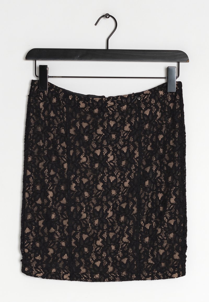 Jupe en dentelle noire suspendue à un cintre, ornée de motifs floraux, d'une texture semi-transparente et d'une coupe ajustée.