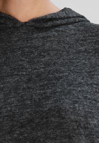 Ciemnoszara bluza z kapturem wykonana z miękkiej, teksturowanej tkaniny. Posiada okrągły dekolt oraz kaptur z troczkami, co wskazuje na swobodny styl.