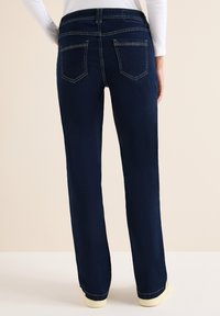 Vaqueros azul oscuro con diseño de pierna recta, que cuentan con dos bolsillos traseros y costuras en contraste. Fabricados con material de mezclilla duradero.