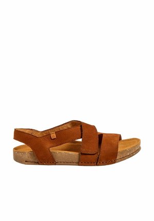Brune ruskind sandals med to overlapping stropper, en polstret indersål og en tekstureret gummisål. Åben bag og justerbar pasform.