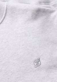 Jasnoszary sweatshirt o miękkiej fakturze i ściągaczu. Na przodzie znajduje się haftowane logo w nieco ciemniejszym odcieniu szarości.