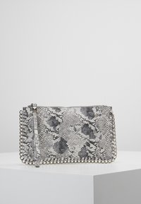 Obdélníková kabelka na clutch s šedým a černým hadím vzorem, stříbrné řetízkové lemování po okrajích a zápěstní pásek na bílé ploše.
