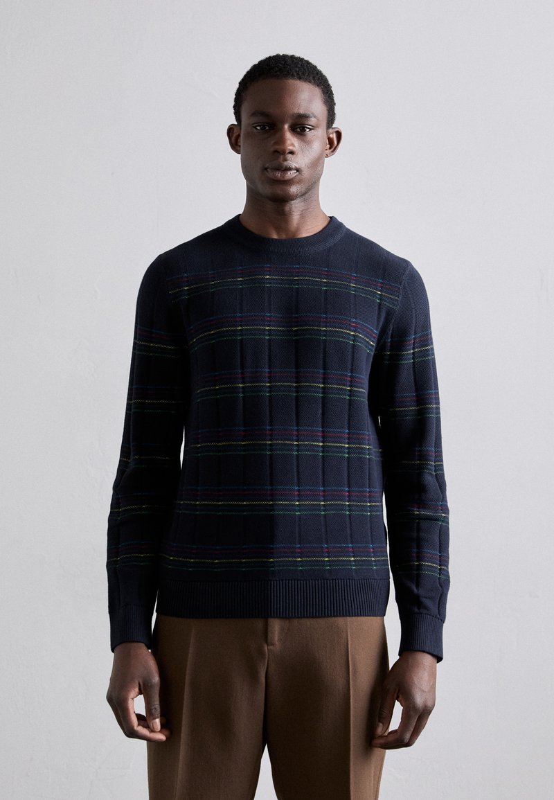 Sweter azul-marinho com um padrão de xadrez apresentando riscas verdes, vermelhas e amarelas. Punhos e bainha canelados, feito de um material de malha texturizada.