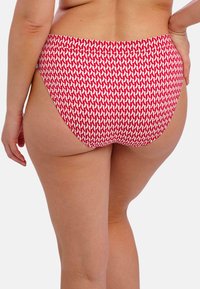 Vysoké bikinové kalhotky v červené barvě s bílým geometrickým vzorem. Tkanina vypadá hladce, má elastický pas a minimální pokrytí vzadu.