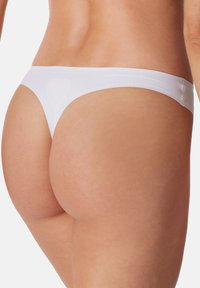 Witte stringonderbroek met een subtiel hartdesign, een zachte textuur en een minimalistische tailleband, die een gestroomlijnde pasvorm benadrukt.