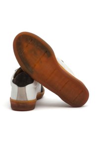Weisse Sneaker mit braunen Wildleder-Akzenten, flachen Gummisohlen und einem strukturierten Profil. Das Design zeichnet sich durch kontrastierende Materialien und Nähte aus.
