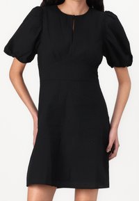 Czarna krótka sukienka wykonana z teksturowanej tkaniny, z bufiastymi rękawami, okrągłym dekoltem z wcięciem oraz sylwetką w kształcie litery A.