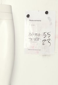 Feuille blanche avec des mesures écrites à la main, attachée à une surface claire, notant la taille de chaussure et les longueurs : extérieure 55, intérieure 23.