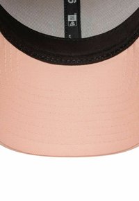 Cappello da baseball rosa con visiera nera, caratterizzato da un tessuto texturizzato e cuciture a contrasto. L'interno presenta una fodera in rete e un'etichetta.