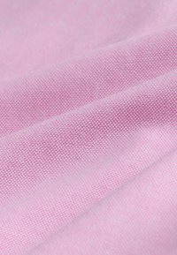 Tessuto rosa con superficie testurizzata e un sottile motivo a griglia, che presenta morbide pieghe e una finitura liscia.