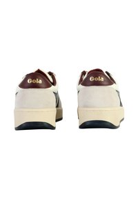 Baskets blanches et gris foncé en matériaux suédés et synthétiques, avec un embout de talon bordeaux et un logo doré "Gola" à l'arrière.