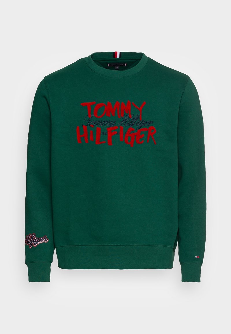 Felpa verde con collo rotondo, presenta un vistoso testo rosso e nero "TOMMY HILFIGER" sul davanti e il logo ricamato sulla manica sinistra.