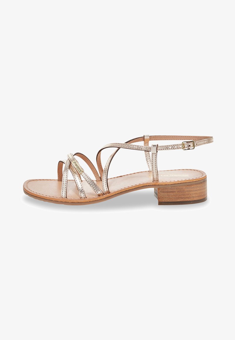 Sandalo con cinturini caratterizzato da una finitura metallica, cinturino alla caviglia regolabile, tacco in legno piatto e design open toe con una soletta in pelle liscia.