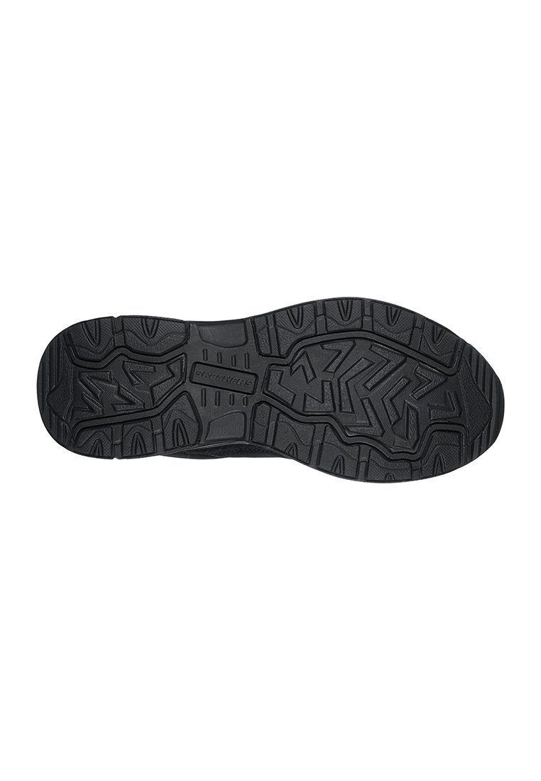 La suela de la zapatilla negra presenta una superficie de goma texturizada con un patrón en zigzag, diseñada para ofrecer tracción y durabilidad, con refuerzos en la puntera y el talón.