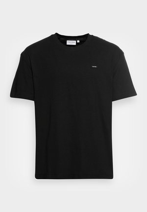 Camiseta de algodón negra con cuello redondo, mangas cortas y un pequeño logo de Calvin Klein en el pecho. Diseño simple y de corte recto.