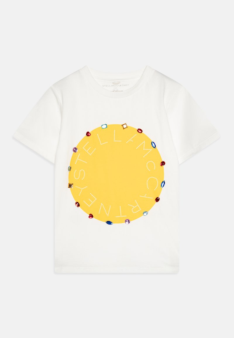 Balts kokvilnas T-krekls ar lielu dzeltenu apli, kas izrotāts ar dārgakmeņiem līdzīgiem akcentiem. Uz akcenta ir teksts "STELLA McCARTNEY", kas apkārt aplim ir sakārtots.