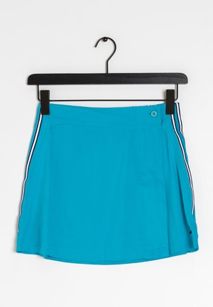 Jupe de sport turquoise avec des rayures latérales blanches et marines, fermeture à bouton et petit logo près de l'ourlet, suspendue sur un cintre noir.
