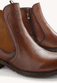 Bruna läderankelboots med texturerade sidopaneler, dragkedjestängning och stickat detaljer. Har en robust sula för bra grepp.