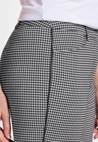 Schwarz-weiße Gingham-Karohosen mit einer taillierten Silhouette, hinteren Taschen und einem flachen Frontdesign mit kontrastierenden Nähdetails.