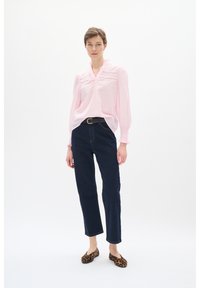 Lyserød langærmet bluse med broderede detaljer, parret med mørkeblå lige jeans og brune leopardmønstrede flade sko.