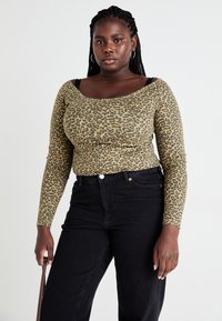 Leopard print long-sleeve top in earthy tones, featuring a scooped neckline and fitted design, paired with black high-waisted jeans.
