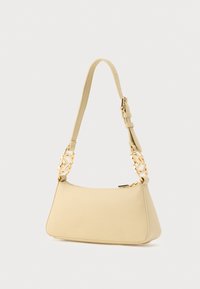 Κίτρινη δερμάτινη τσάντα χειρός με υφή, διακοσμημένη με χρυσή αλυσίδα στο λουρί και κλείσιμο με φερμουάρ. Λεπτό, τραπεζοειδές σχήμα.