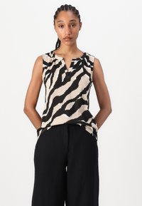 Top senza maniche caratterizzato da una stampa a zebre in bianco e nero, con scollatura a V e vestibilità rilassata, abbinato a pantaloni neri a gamba larga.