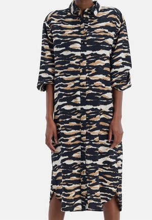 Knopfleisten-Kleid, langärmlig, knielang, mit abstraktem Tigerstreifenmuster in Schwarz, Beige und Weiß auf einer Person.