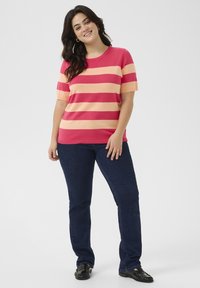 Top de manga corta a rayas en rosa y crema, diseño de cuello redondo, combinado con jeans de mezclilla azul oscuro y zapatos planos negros.