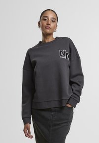 Sweatshirt court gris foncé avec des épaules tombantes, des poignets côtelés et un logo "NM" blanc sur la poitrine gauche. Texture lisse, design décontracté.