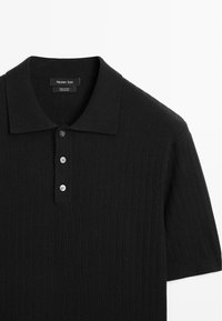 Polo noir côtelé à manches courtes avec trois boutons et un col pointu, étiqueté Massimo Dutti, fabriqué en 100 % coton.