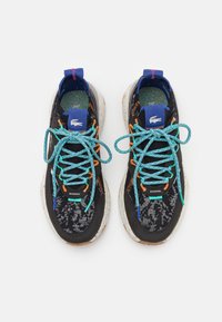 Zapatillas negras con un upper texturizado, cordones vibrantes en azul y naranja, una entresuela blanca moteada y una etiqueta de logo en la lengüeta.