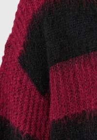 Sweter dzianinowy z odważnym wzorem burgundowych i czarnych pasków, teksturowana przędza oraz lekko puszysty wygląd.