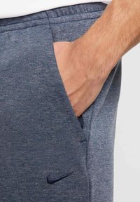 Nike Jogginghosen aus dunkelblauem Heather-Stoff, ausgestattet mit einer Seitentasche und gesticktem Logo. Der elastische Bund sorgt für einen besseren Sitz und mehr Komfort.