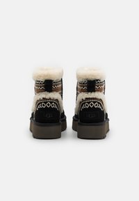 Botas de tobillo de ante negro con forro de borreguito crema, acentos de tela con patrones en tonos cálidos y una suela de goma marrón resistente.