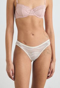 Light pink lace bra with underwire and adjustable straps, paired with white mesh panties featuring wave patterns and a soft waistband.