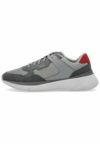 Grauer Sportschuh mit Netzpaneelen, Wildlederakzenten und einer wei�ßen Sohle. Verfügt über eine rote Fersenschlaufe und ein metallisches Logo an der Seite.