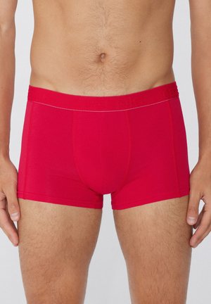 Rote Boxer Shorts aus dehnbarem Stoff mit elastischem Bund, die eine glatte Textur und Nahtdetails an der Vorder- und Seitenpartie aufweisen.