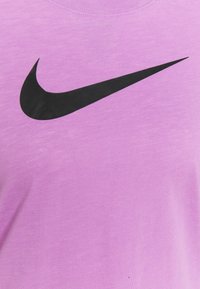 T-shirt en coton violet avec un grand logo Nike swoosh noir, col rond et un tissu doux et texturé.