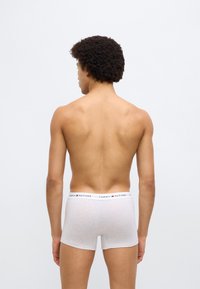 Λευκά αντρικά μπόξερ από βαμβάκι με λάστιχο στη μέση που φέρει εκτυπωμένο λογότυπο. Το ύφασμα φαίνεται μαλακό, με διακριτική υφή. Η εφαρμογή είναι στενή και μοντέρνα.