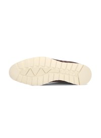 Brown sneaker outsole featuring a textured cream rubber sole with a triangular pattern, embossed logo, and deep grooves for traction.