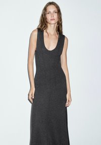 Robe sans manches gris foncé en tissu lisse et extensible, avec un décolleté plongeant et une coupe ajustée avec des coutures verticales.