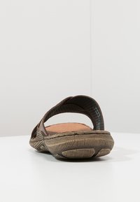 Sandale marron avec deux sangles ajustables, semelle en caoutchouc texturée et semelle intérieure rembourrée. La vue arrière montre une forme arrondie et des matériaux flexibles.