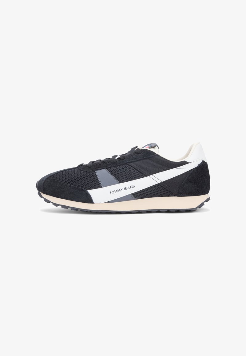 Baskets noires et grises avec une tige en mesh, des accents en suède, un logo blanc et un design à rayures, ainsi qu'une semelle en caoutchouc texturée.