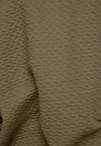 Textured olive green fabric with a wavy pattern, soft to the touch and draping smoothly, suggesting a lightweight textile suitable for clothing.
