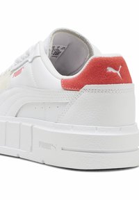 Sneaker bianca con parte superiore in pelle con texture, tallone in suede rosso a contrasto e suola in gomma spessa. Presenta un logo prominente sul lato.