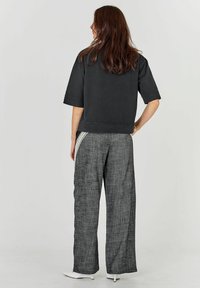 Sweatshirt negru scurt cu mâneci scurte, asortat cu pantaloni largi gri texturați, cu dungi verticale pe laterale.